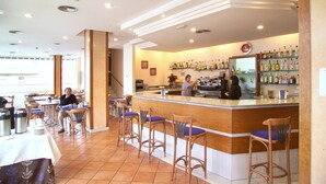 A restaurant with a bar area, wooden chairs, and a tiled floor. - Hotel J. Balmes Vic (Vic)