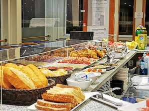 Un buffet proposant une variété de plats, notamment du pain, des pâtisseries et de la viande.