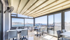 Ein moderner Konferenzraum mit großen Fenstern, einem Ventilator und Blick auf Stadt und Meer.