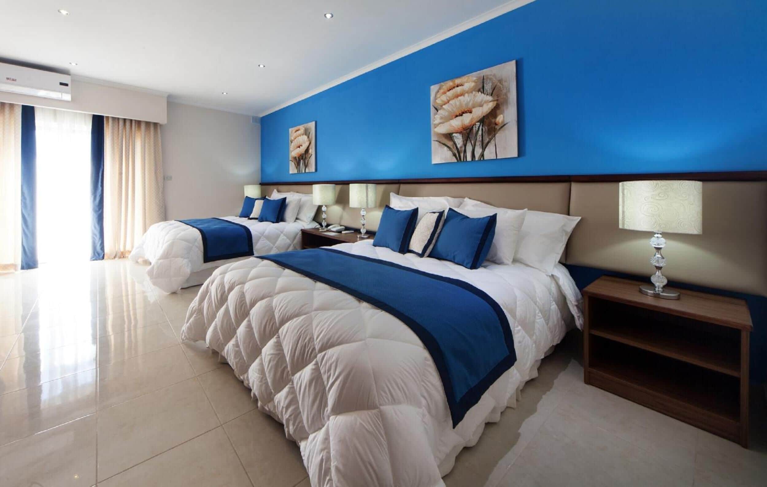 A modern hotel room with a large bed, two bedside tables, and artwork on the walls.