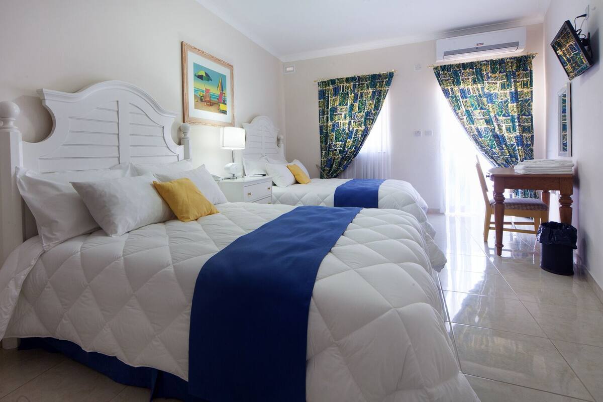 Habitación de hotel con dos camas, un escritorio y una silla.