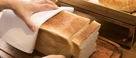A loaf of bread being sliced on a wooden cutting board.