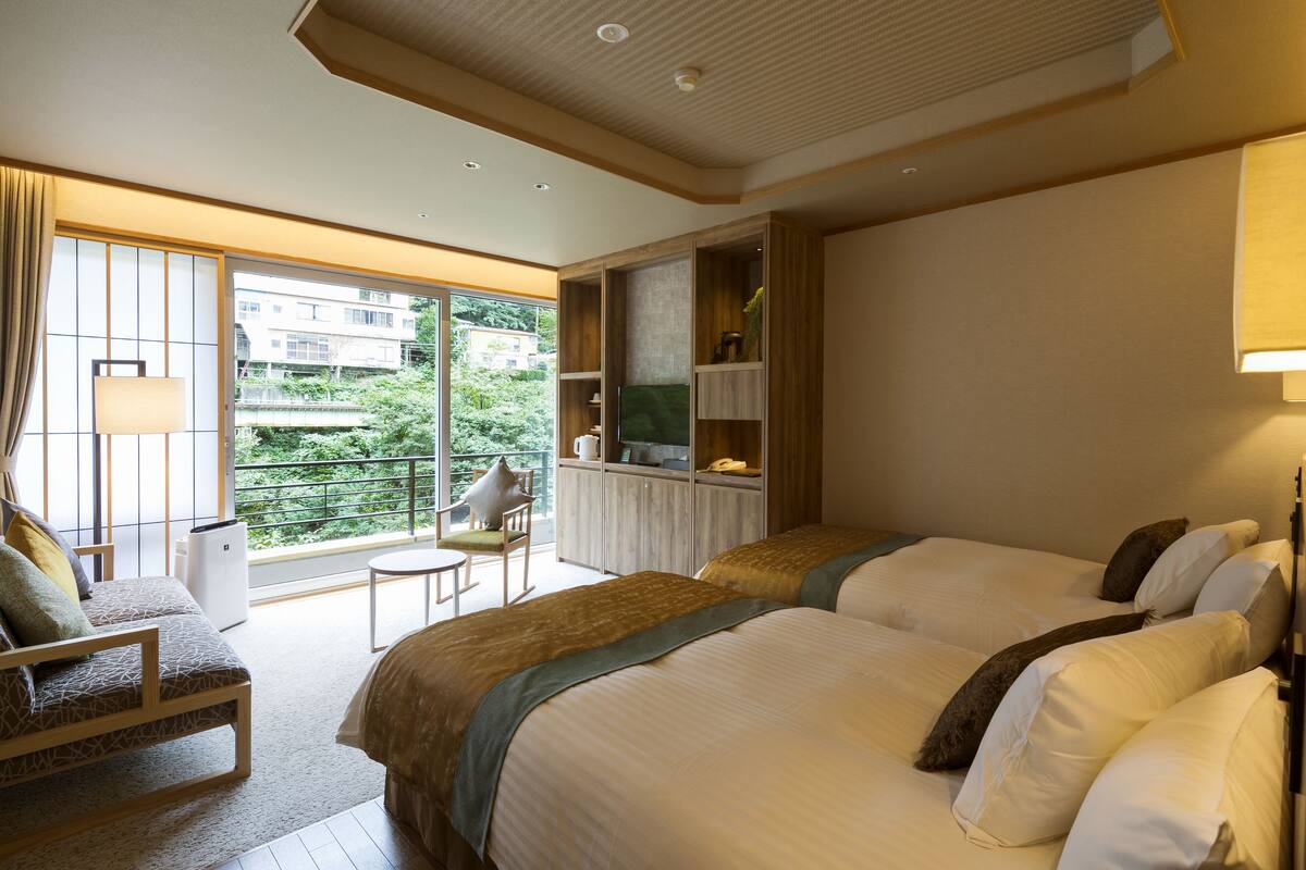 A hotel room with two beds, a sofa, a small table, and a TV.