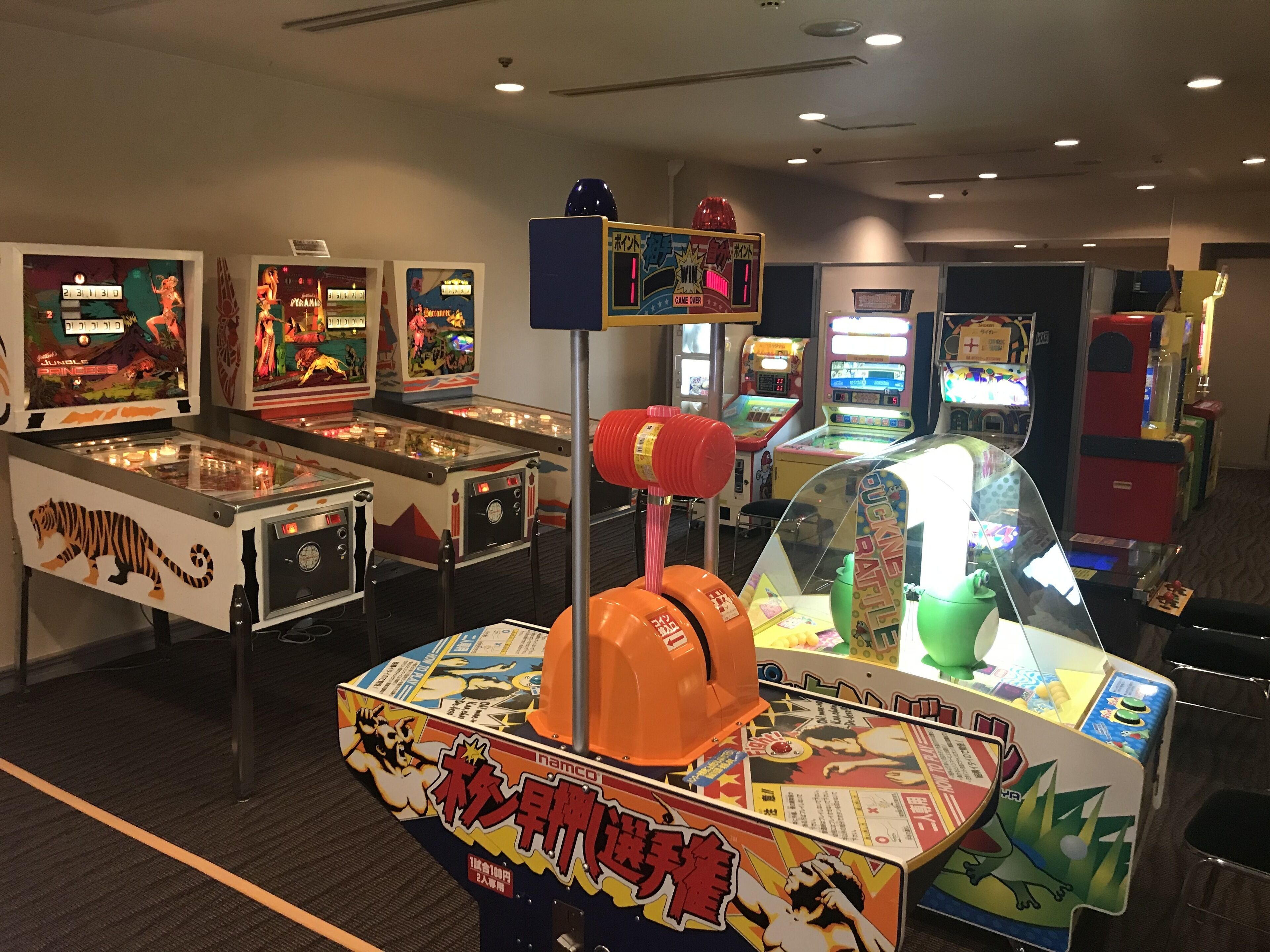 A row of arcade games with a variety of colorful designs and Japanese text.