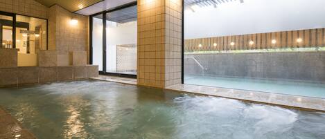 A modern indoor pool area with clear glass walls, a tiled floor, and a wooden ceiling.