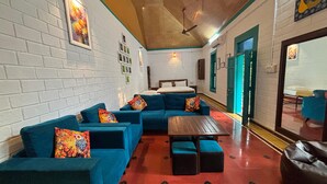 A room with a sectional sofa, a small table, and a bed. - Anamala Serenity Homestay (Talappilly)