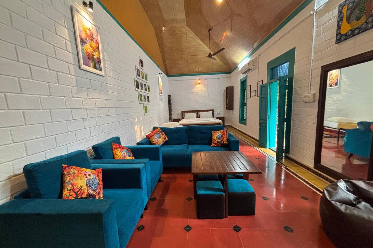 A room with a sectional sofa, a small table, and a bed.