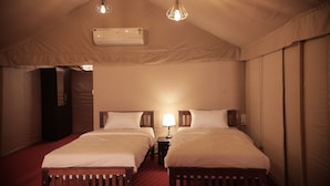 A room with two beds, a nightstand with a lamp, an air conditioner, and a hanging light fixture. - Anamala Serenity Homestay (Talappilly)