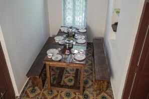 A dining area with a wooden table set for four, surrounded by chairs. - Anamala Serenity Homestay (Talappilly)