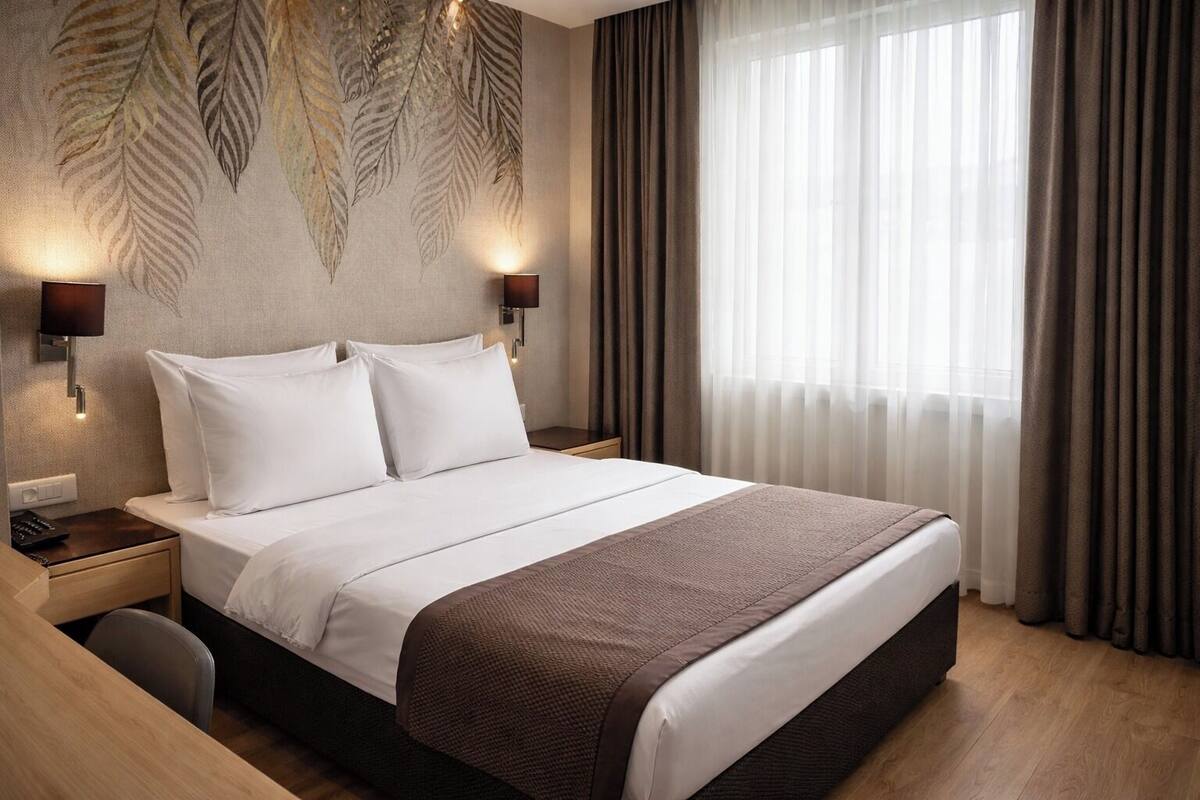 A hotel room with a large bed, two bedside tables, a nightstand, a desk, and a chair.