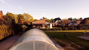 Uma estufa com teto curvo, rodeada por um gramado bem cuidado e um deck de madeira.