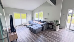 Uma sala de estar moderna com um sofá modular cinza, uma mesa de centro de vidro e uma mesinha lateral com uma planta.