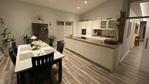 Uma cozinha moderna com armários brancos, uma ilha central e um espaço de jantar com mesa e cadeiras.