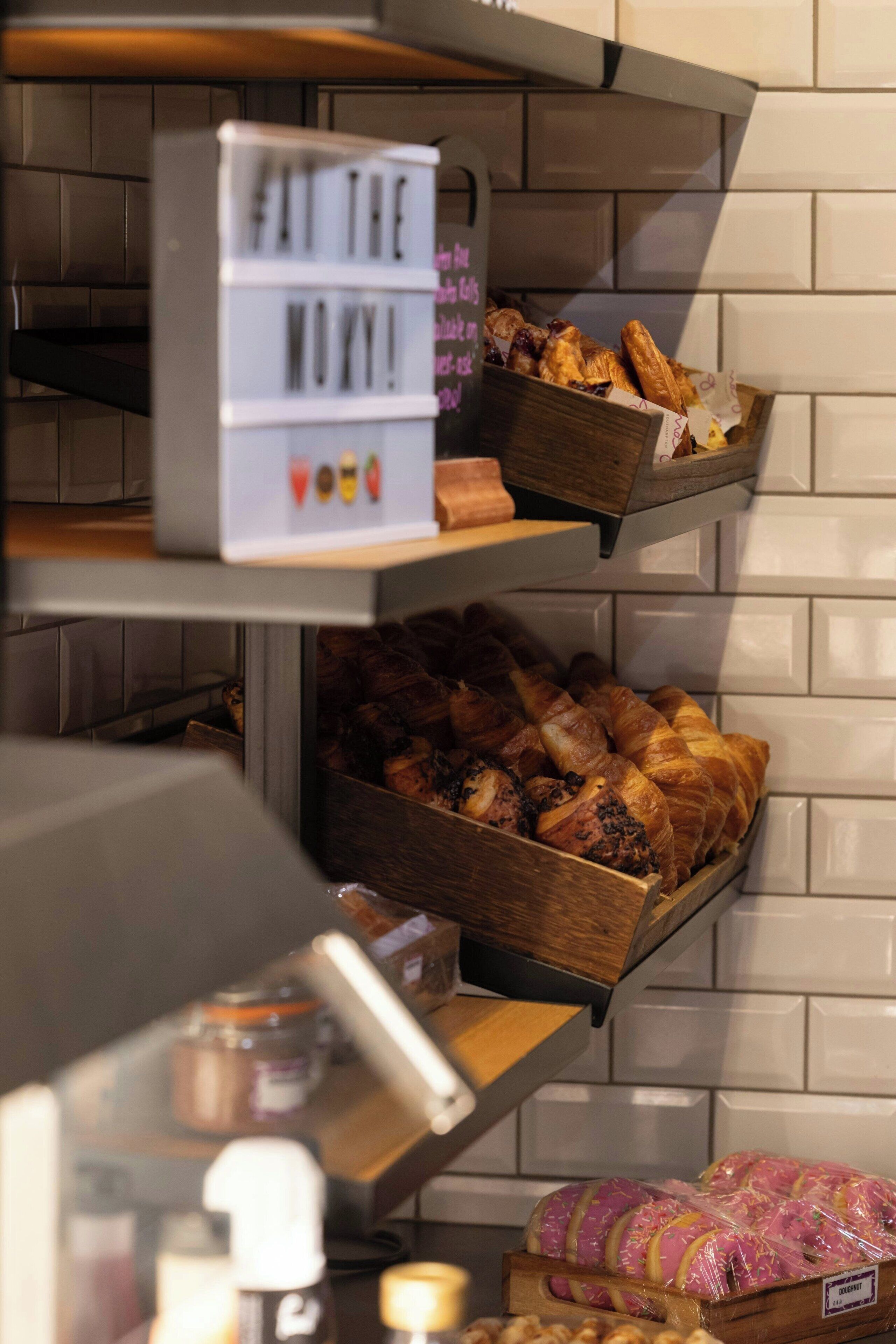 Una vitrina de panadería con diversos productos horneados y un letrero que dice 'FAT THE WOW!'.