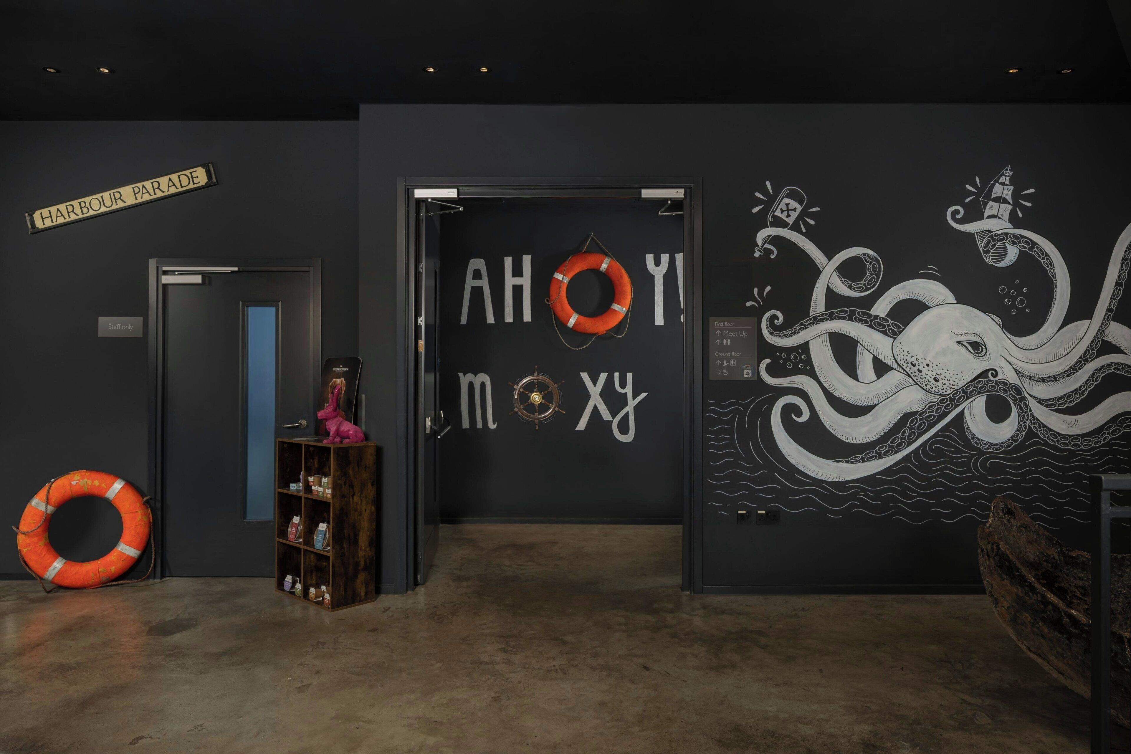 A hallway with a sign reading "Harbour Parade," a life preserver, and a bookshelf with various items.