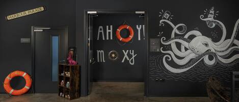 A hallway with a sign reading "Harbour Parade," a life preserver, and a bookshelf with various items.
