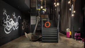 A modern interior with a staircase, decorative wall art, and hanging lights. - Moxy Southampton (Southampton)