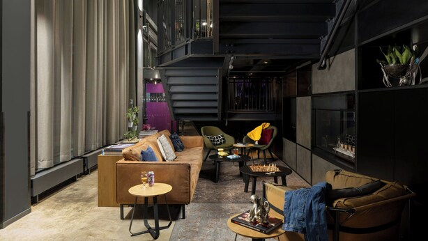A modern interior with a sofa, chairs, a coffee table, and a bookshelf. - Moxy Southampton (Southampton)