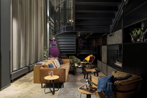 A modern interior with a sofa, chairs, a coffee table, and a bookshelf. - Moxy Southampton (Southampton)