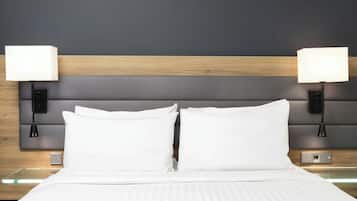 A neatly made bed with white linens and two bedside lamps on a wooden headboard.