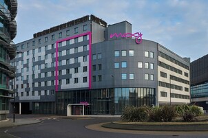 A modern hotel with a curved facade, large windows, and a prominent pink accent wall.