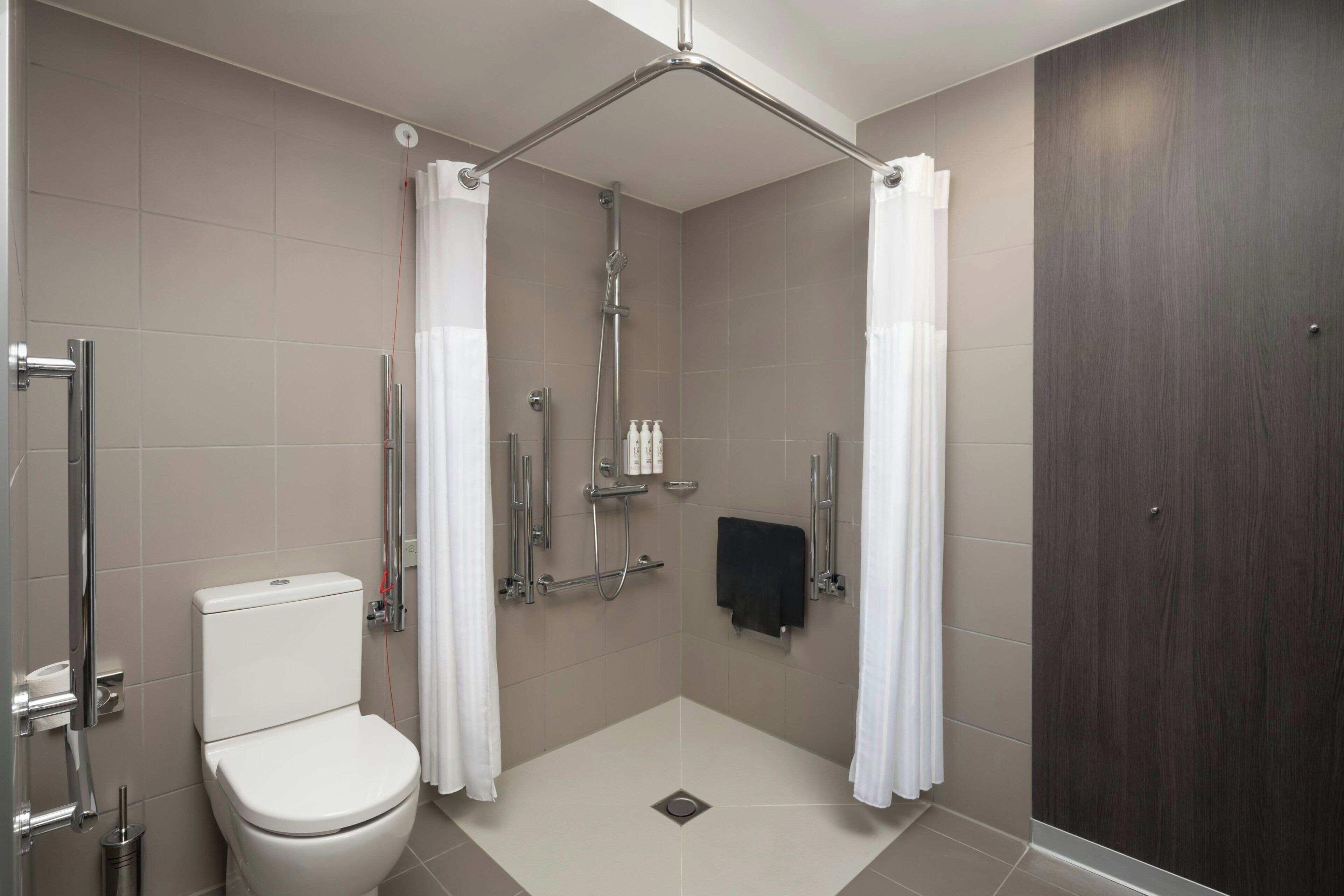 A modern bathroom with a shower, toilet, and a towel rack.