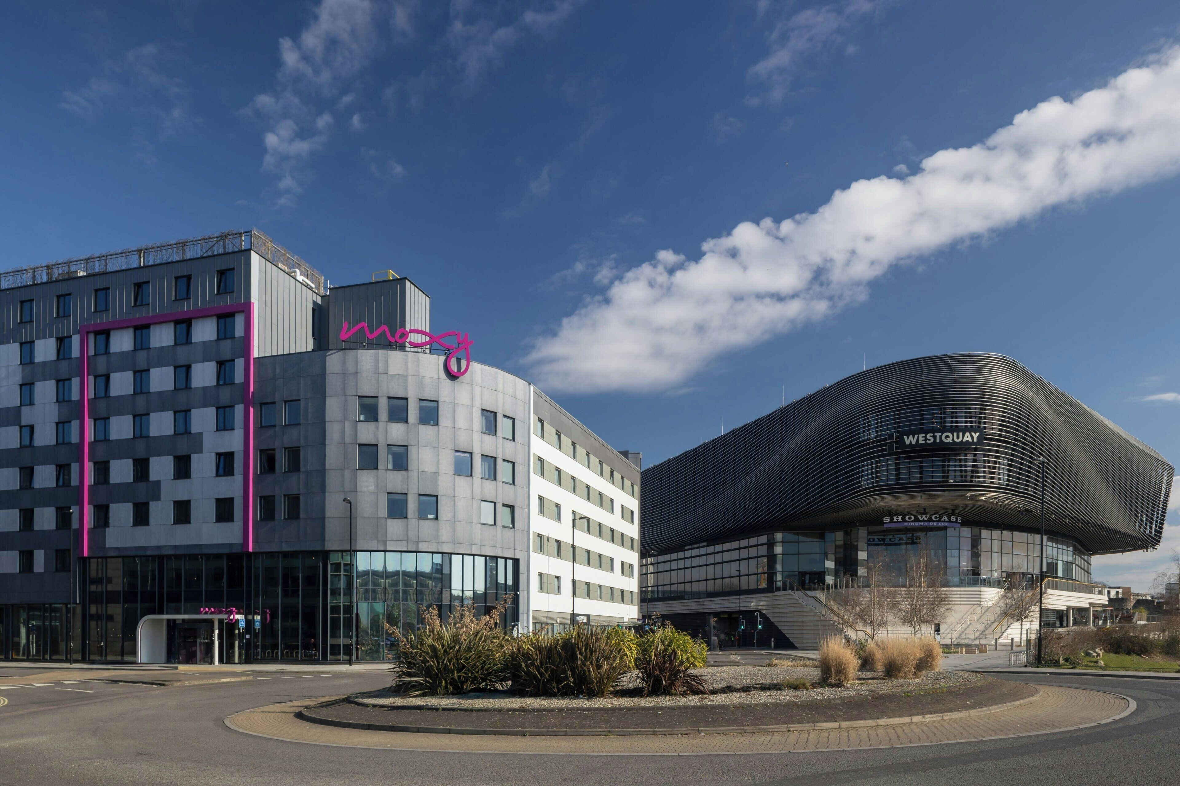 A modern building with a curved facade and a sign that reads "WestQuay."