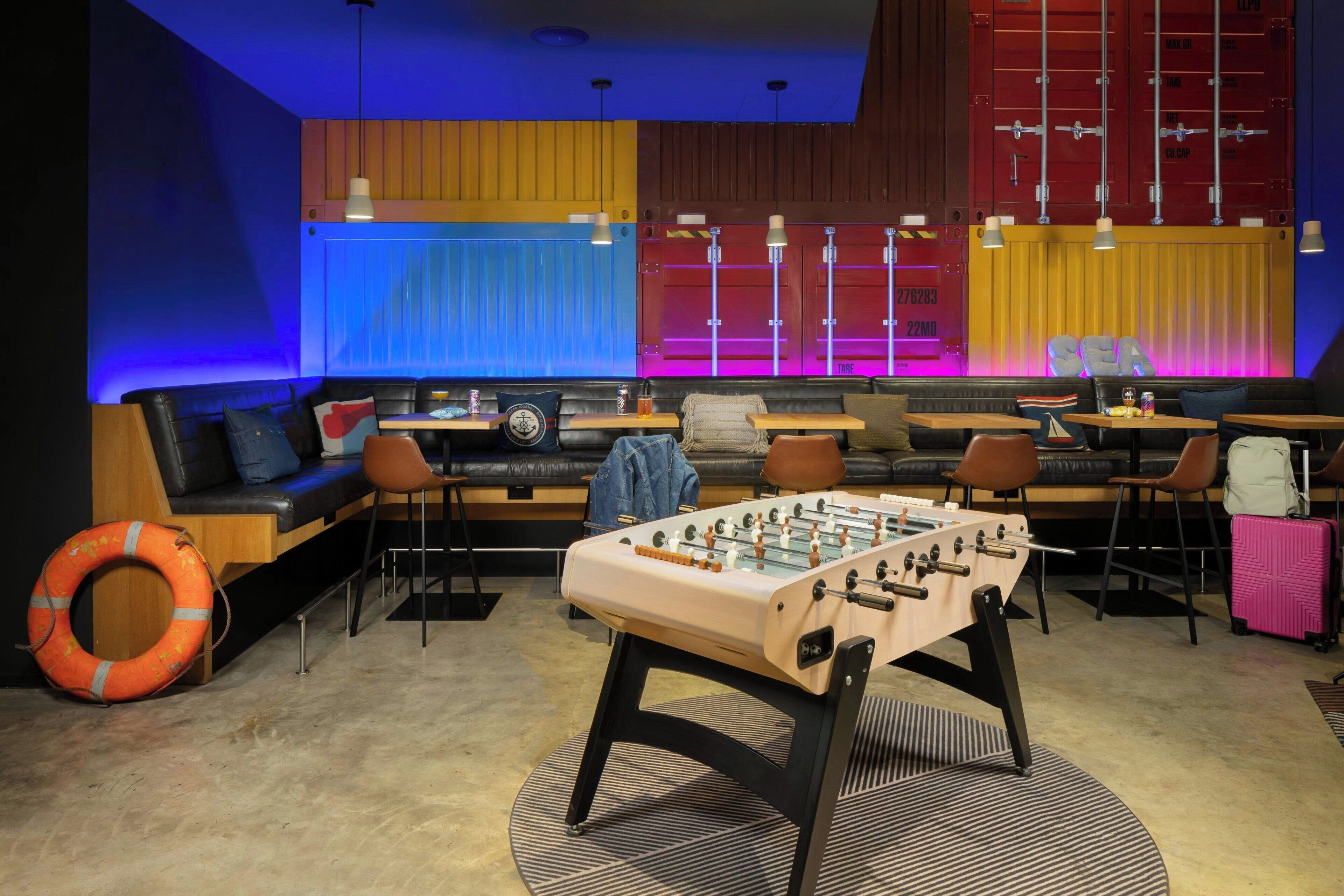 A room with a foosball table, sofas, and a foosball table with a life preserver on the floor.