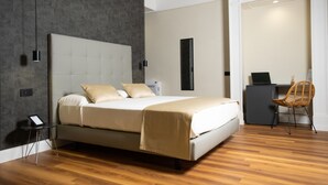 A modern bedroom with a large bed, a desk, and a chair. - Nova Relais (Naples)