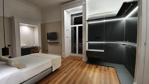 Un dormitorio con cama, escritorio, televisor y vestidor.
