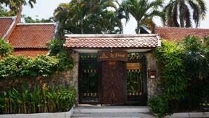 A traditional Thai building with a tiled roof, a stone wall, and a wooden gate. - Le Prive Resort (Pattaya)