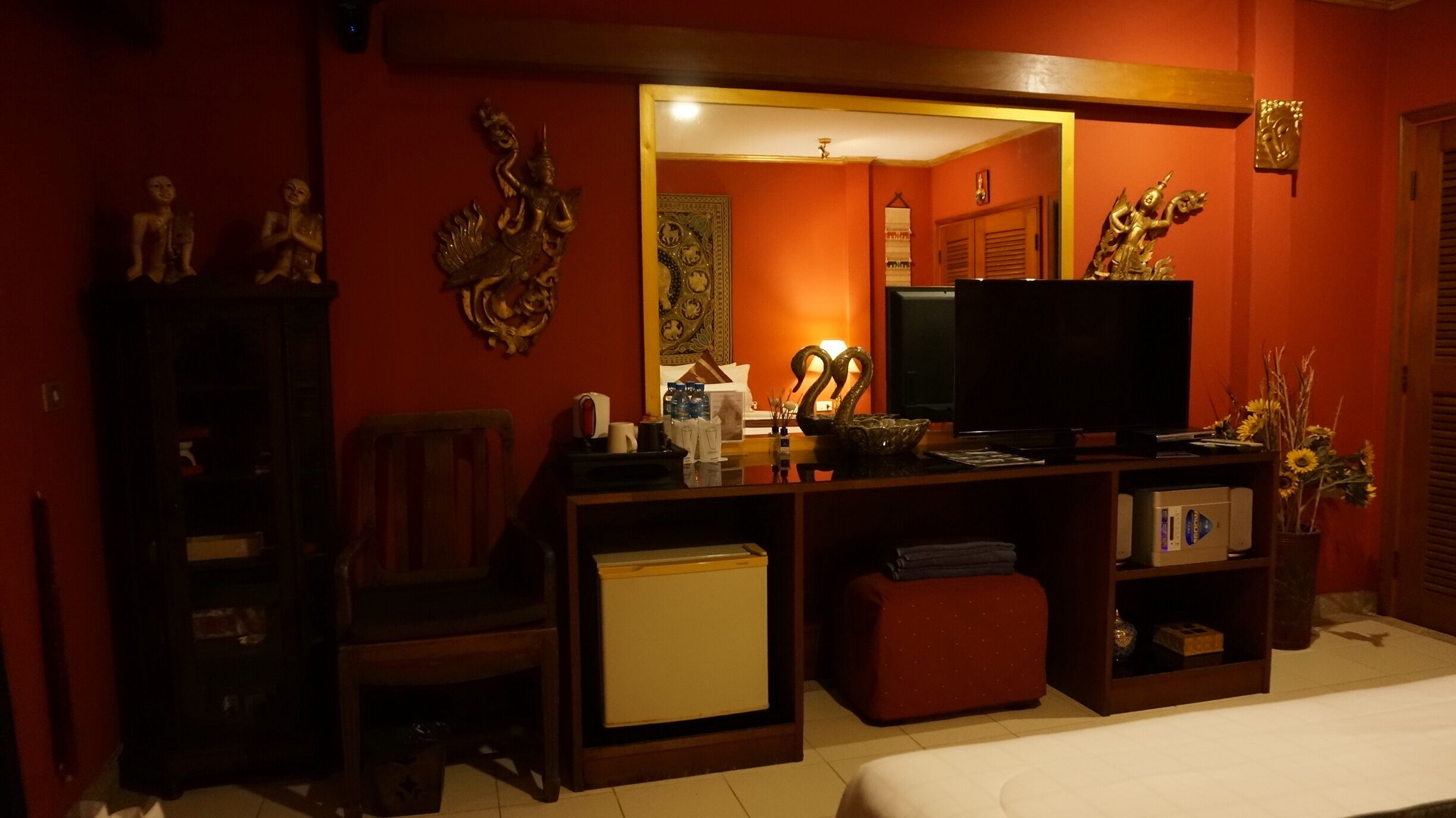 A hotel room with a television, a small refrigerator, a wooden cabinet, a sofa, and a bed.
