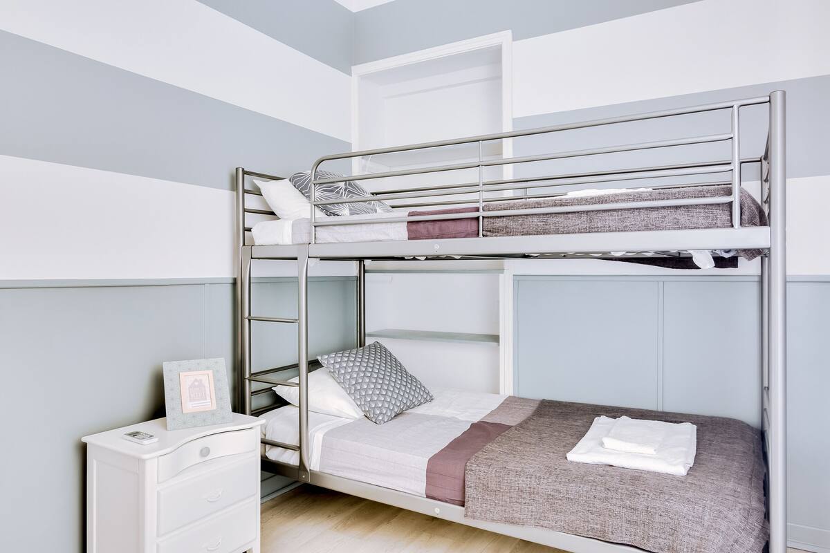 A bunk bed room with a white dresser and a framed picture on it.