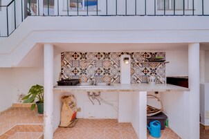 Una cocina compacta con salpicadero de azulejos, un lavamanos y una pequeña encimera.