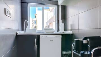 A compact kitchen with a refrigerator, sink, and coffee machine.