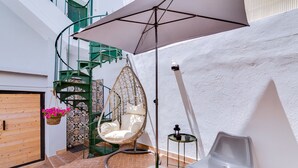 A patio area with a hanging chair, a small table, and a plastic chair. - À da Avó - The Guesthouse (Faro)