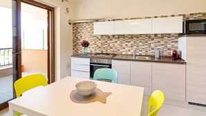 A modern kitchen with white cabinets, a tiled backsplash, and a dining area with a table and chairs.