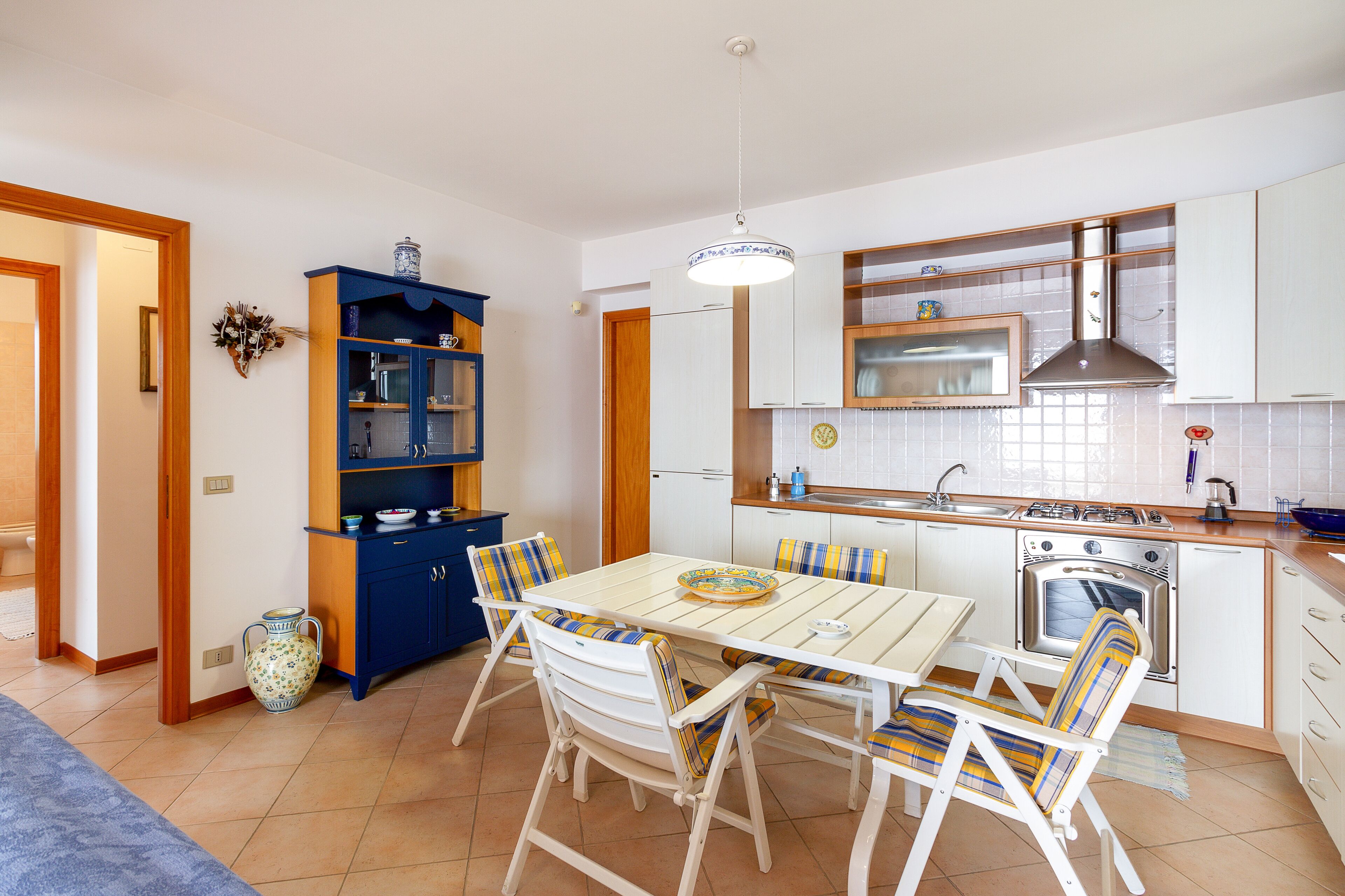 A compact kitchen with a dining table, chairs, and a built-in oven.