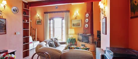 A cozy living room with a sofa, a dining table with flowers, and a fireplace.