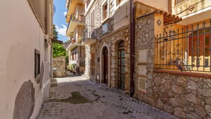 A narrow cobblestone street flanked by stone buildings with arched doorways and balconies. - Taormina Vintage Loft  (Taormina)