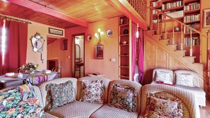 A cozy living room with a checkered sofa set, a wooden staircase, and a bookshelf filled with books. - Taormina Vintage Loft  (Taormina)