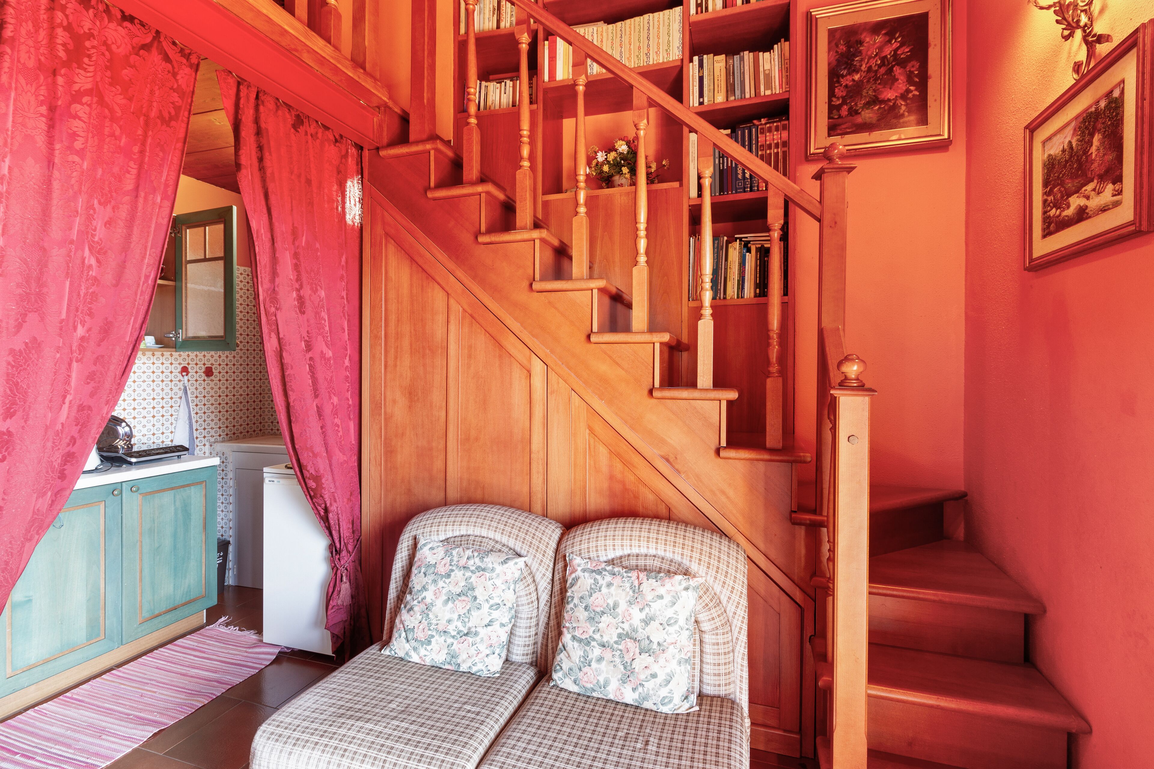 A bedroom with a wooden staircase, a bed with floral pillows, and a bookshelf.