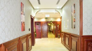 A hotel hallway with wooden paneling, marble flooring, and decorative wall art. - Quiet Rooms 3 (Riyadh)