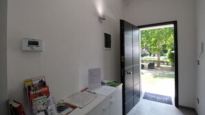 A reception area with a desk, informational brochures, a digital display, and a door leading to an outdoor area with greenery. - R&B San Rafèl (Bologna)