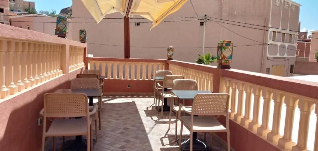A balcony with outdoor seating, including tables and chairs, and a decorative umbrella.