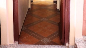 A hallway with a patterned tile floor leading to a room with a patterned door. - Maison d'hote Dar amghar (Tafraout)