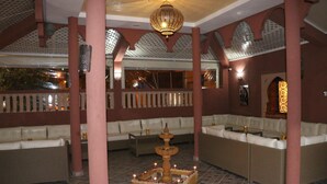 A lounge area with cushioned seating, a decorative fountain, and patterned ceiling. - Maison d'hote Dar amghar (Tafraout)