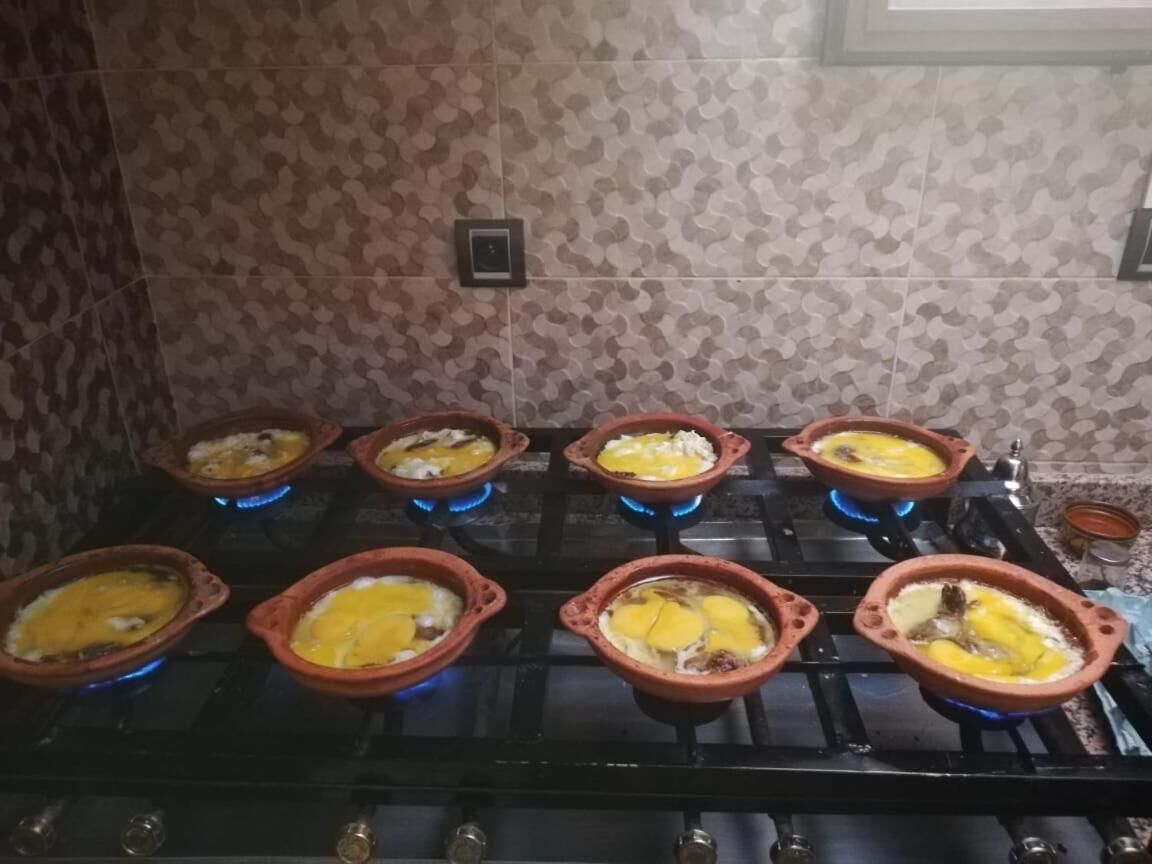 A kitchen with multiple clay pots on a stove, each containing food.