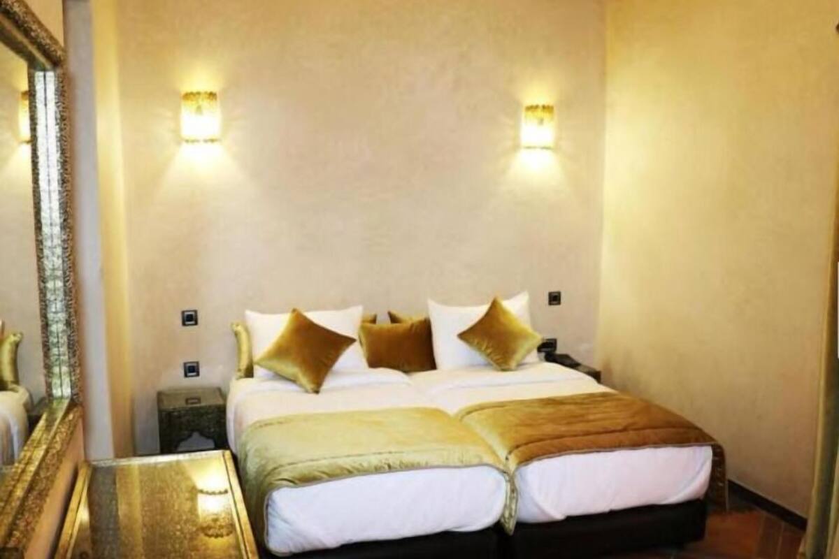 Una habitación de hotel con una cama doble, dos mesitas de noche y dos lámparas de pared.