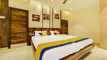 A hotel room with a large bed, wooden headboard, and three wall-mounted artwork pieces.